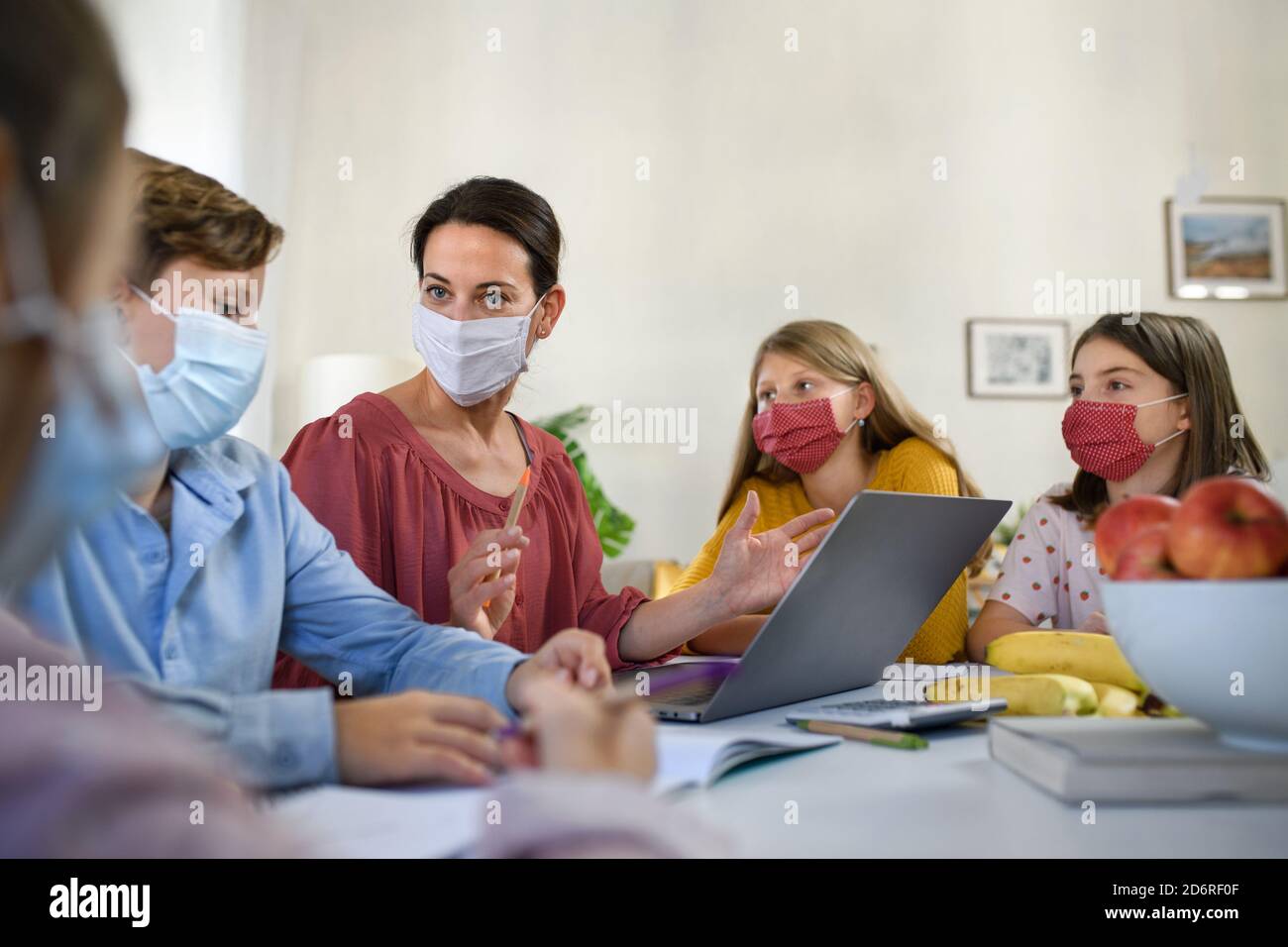 Group of homeschooling children with teacher studying indoors, coronavirus concept. Stock Photo