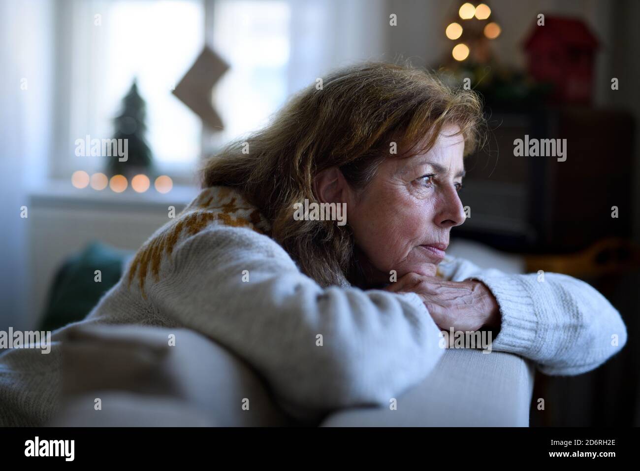 Lonely senior woman sitting on sofa indoors at Christmas, solitude concept. Stock Photo