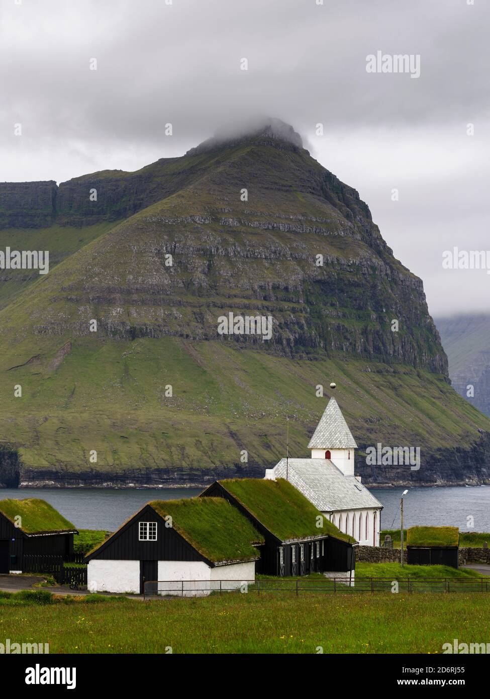 Village Vidareidi with church on the Island Vidoy. View towards Bordoy and Kunoy. Nordoyggjar (Northern Isles) in the Faroe Islands, an archipelago in Stock Photo