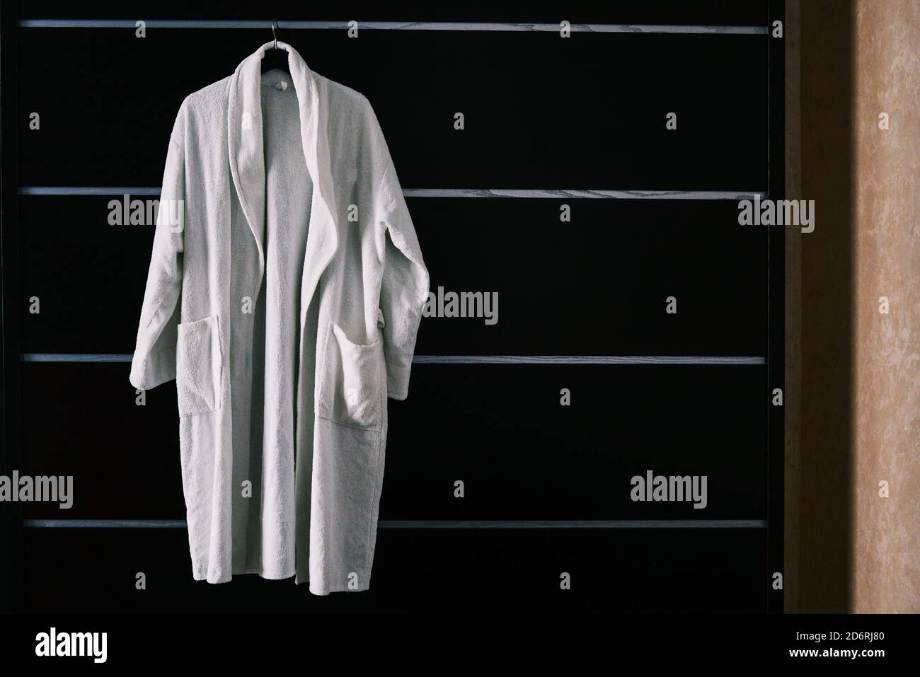 White robe in the hotel room. The hotel bathrobe weighs on a black