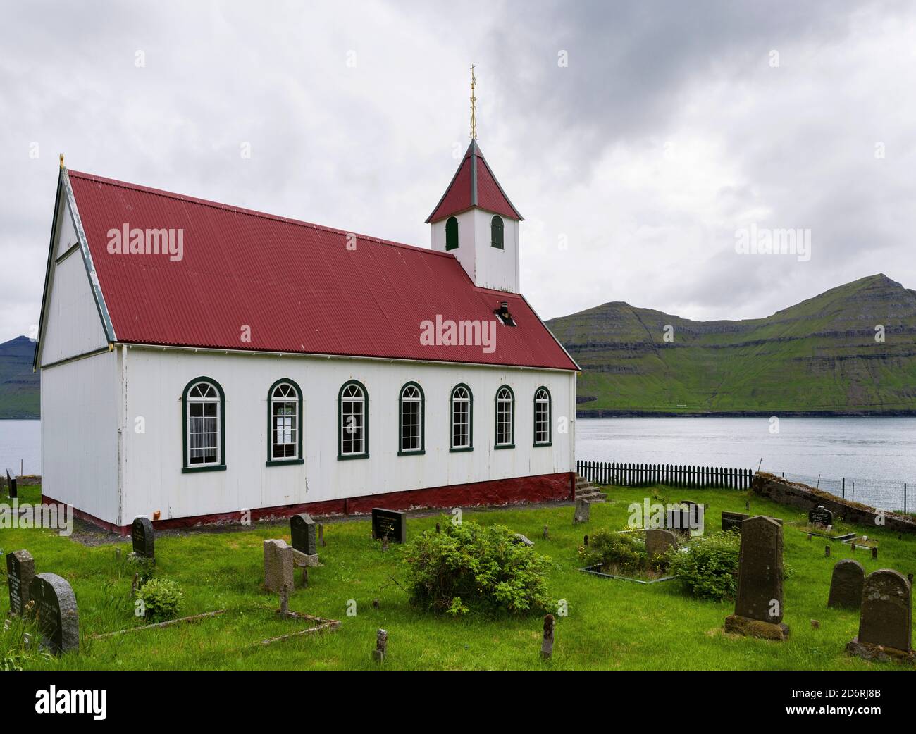The island of  Kunoy with village Kunoy and church. In the background island Kalsoy. Nordoyggjar (Northern Isles) in the Faroe Islands, an archipelago Stock Photo