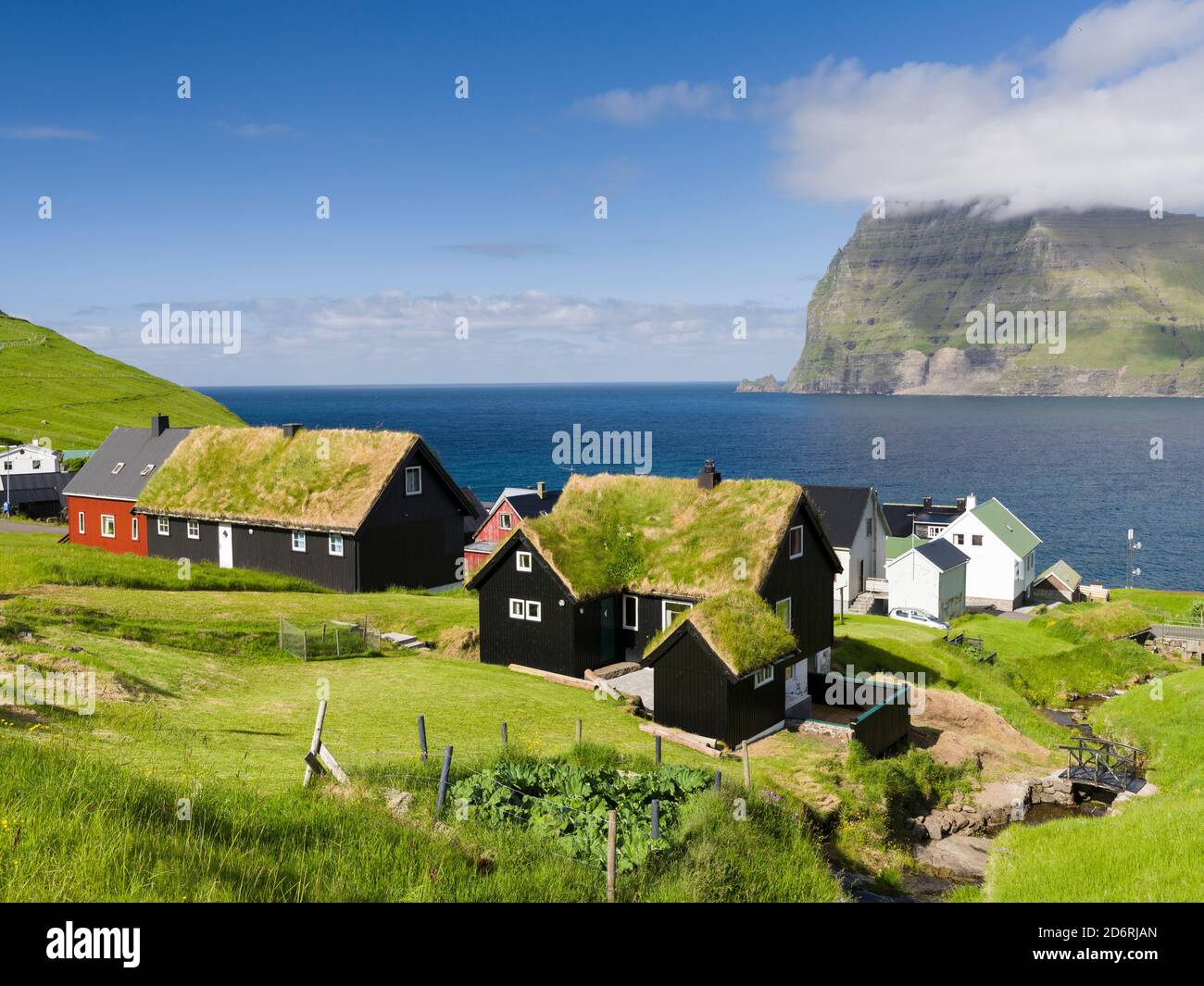 Village Mikladalur, on the Island  Kalsoy, in  background the island Kunoy. Nordoyggjar (Northern Isles) in the Faroe Islands, an archipelago in the n Stock Photo