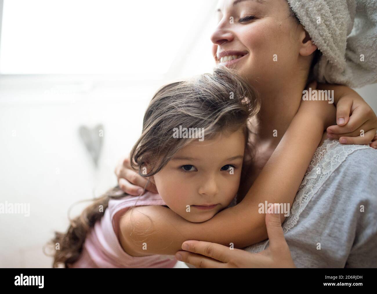 Mother and small daughter indoors at home, hugging. Stock Photo