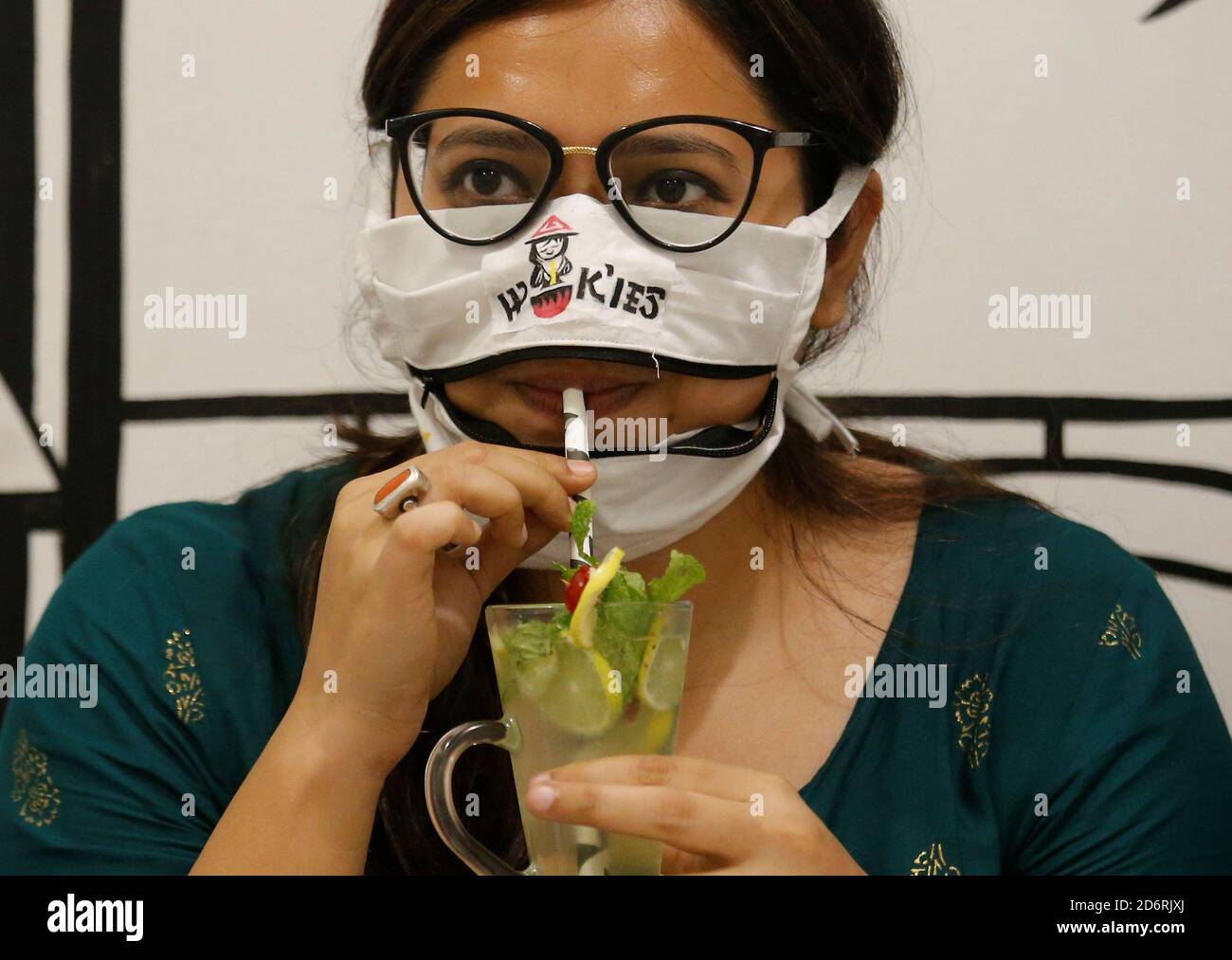 A woman drinks juice using a zip-up mask provided by Wok'ies restaurant in Kolkata, India, October 19, 2020. REUTERS/Rupak De Chowdhuri Stock Photo