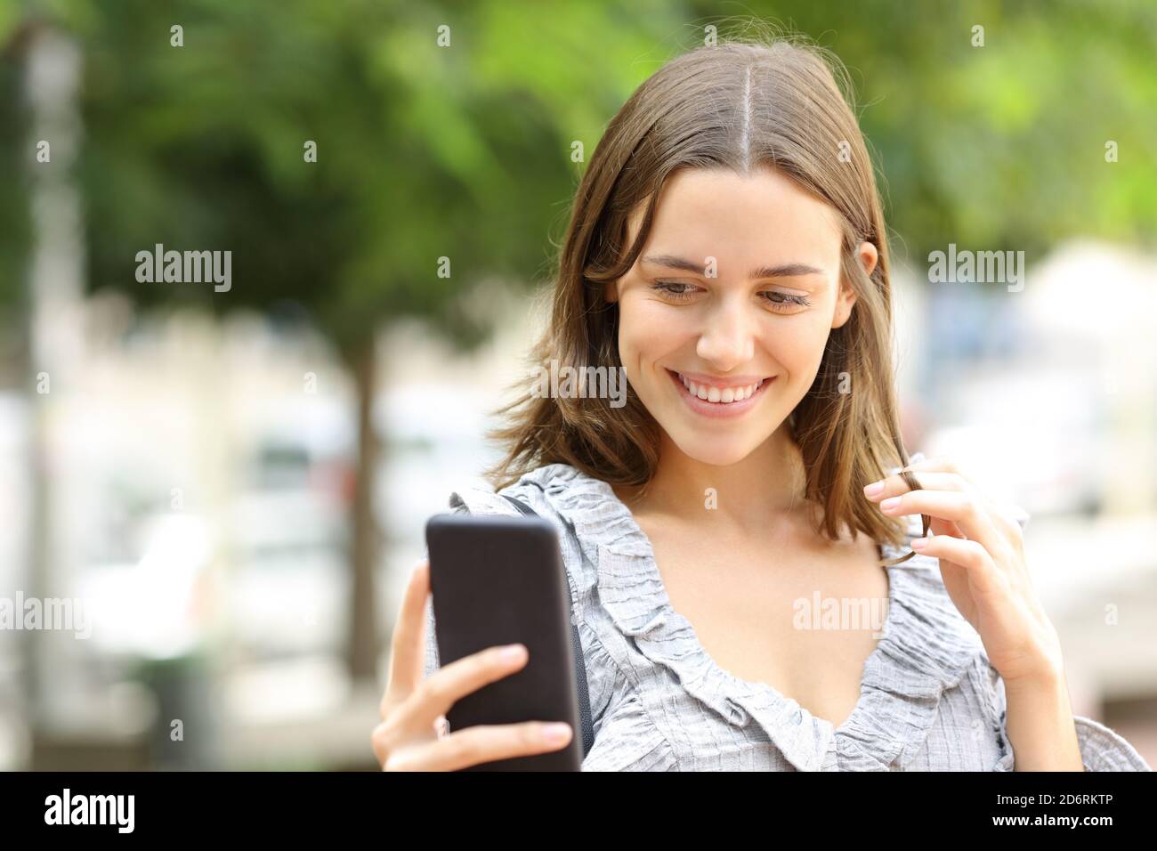 Happy woman flirting online with smart phone in the street Stock Photo