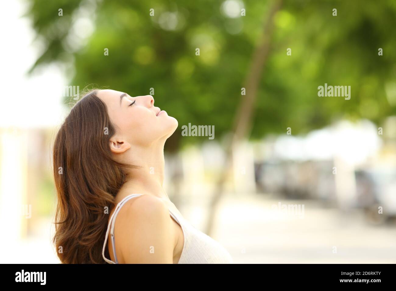 Profile of a beautiful woman breathing fresh air sitting in a park ...