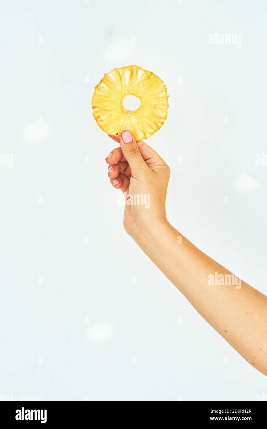Female hand holding pineapple fruit chips on a white background. Stock Photo