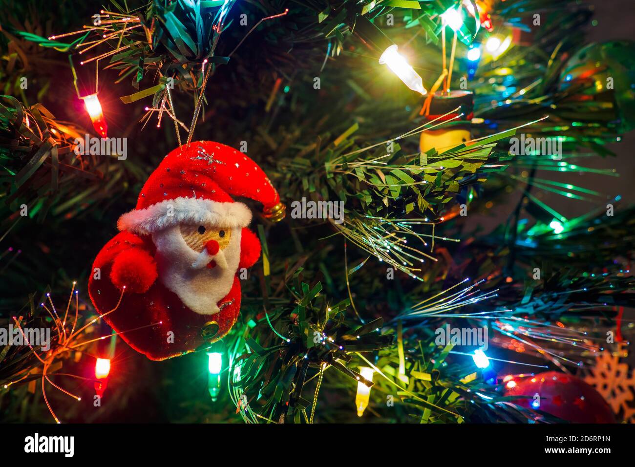 Christmas tree with hanging toy of Santa claus and garland lights. New year card, selective focus Stock Photo