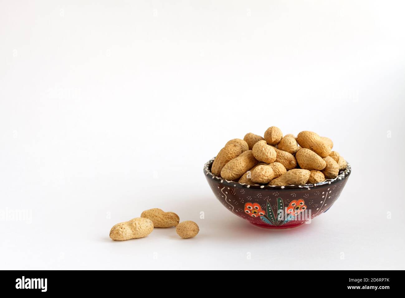 nuts in shell on clay cup on white background, copy space for text Stock Photo