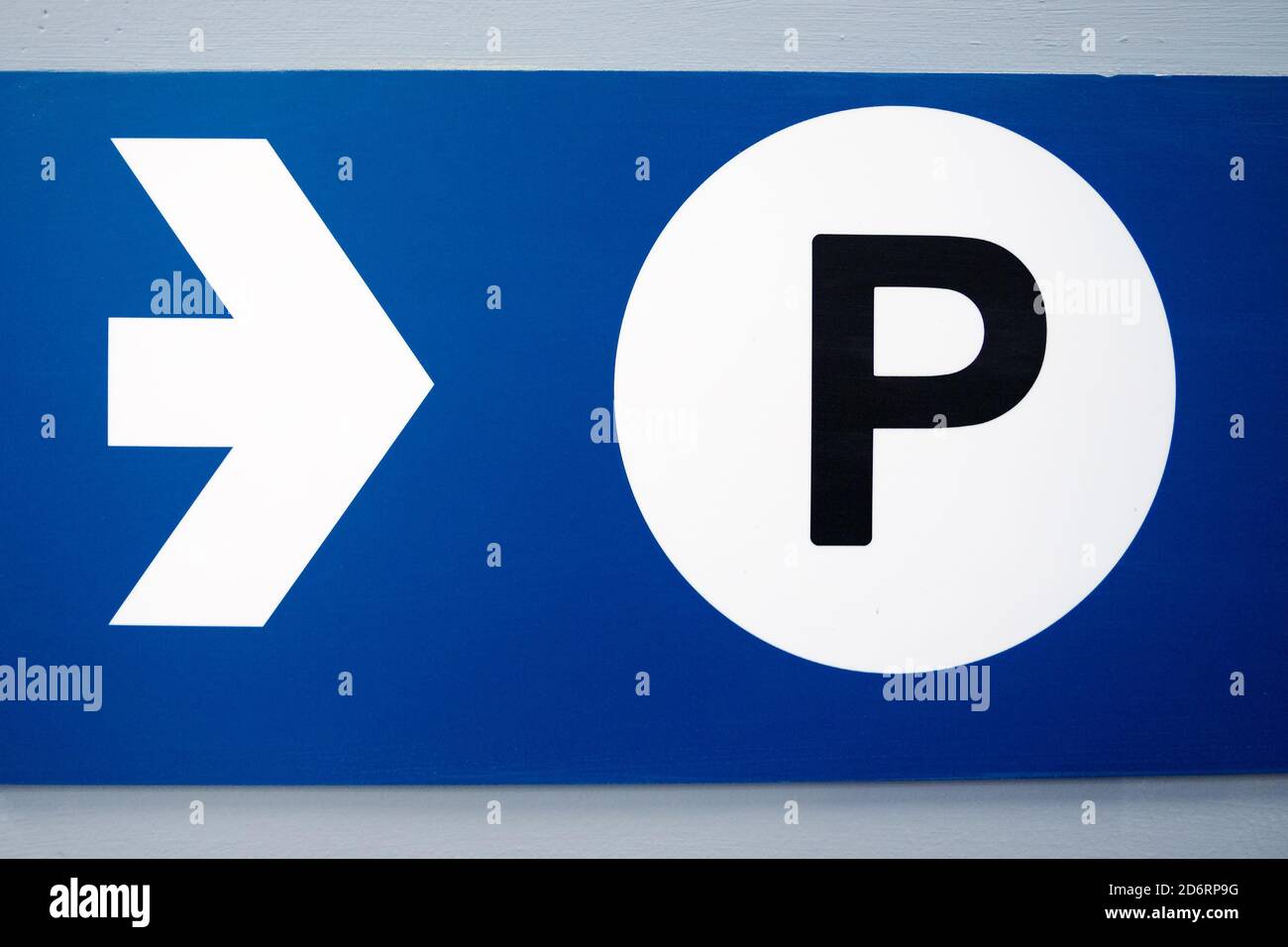 blue parking sign with white arrow and black capital P on white