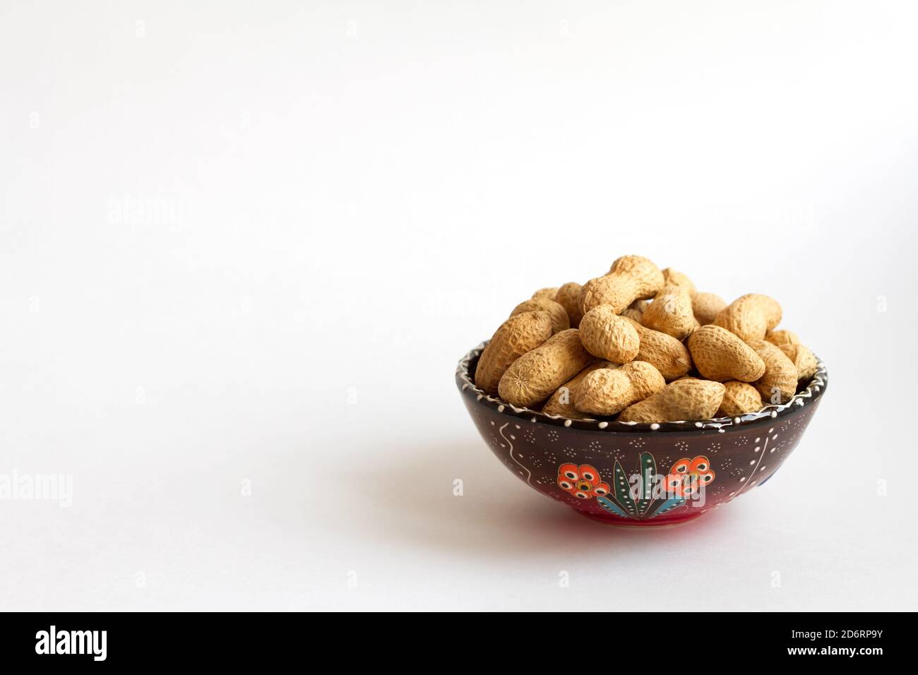 peanuts in shell on clay cup on white background. copy space Stock Photo