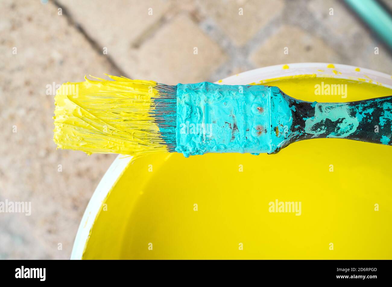 Used flat decorator brush  covered with dry cyan and wet yellow color. Closeup Stock Photo