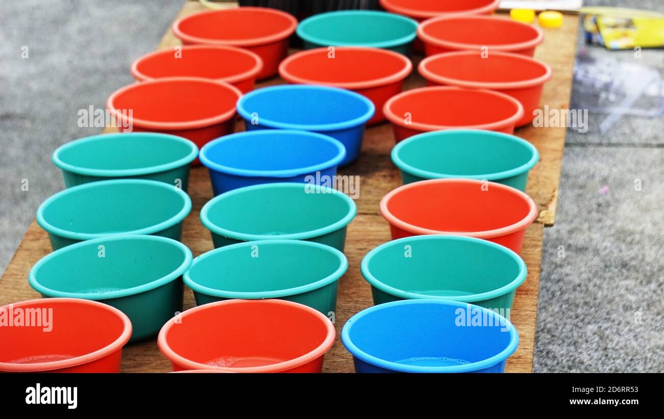 Selling Colorful tubs lined together on a wooden platform. Small plastic tubs filled with soap solution for blowing bubbles. Stock Photo
