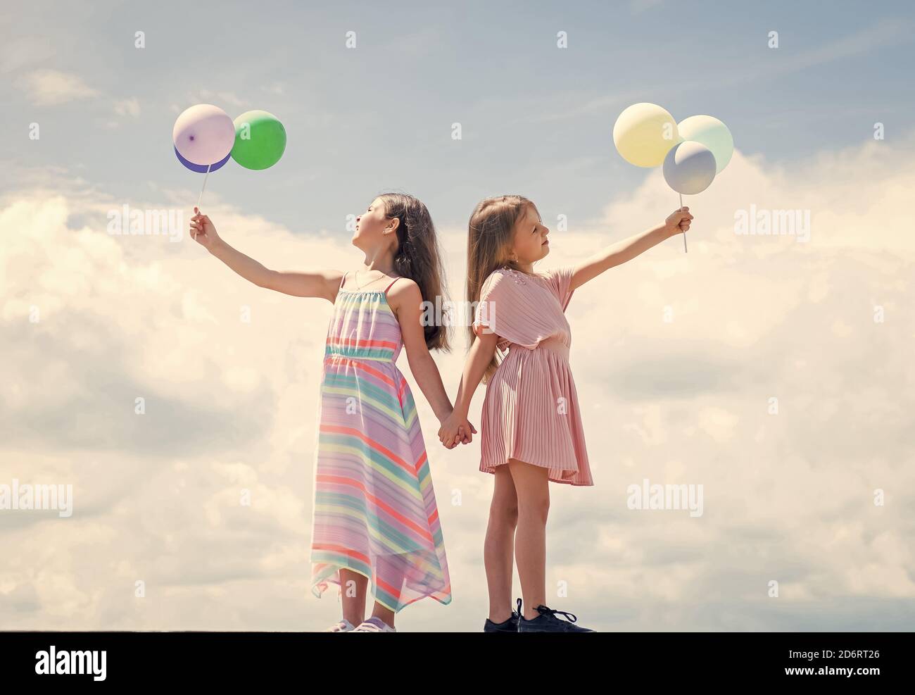 happy childhood. summer vacation. small girls embrace. love and support. concept of sisterhood and friendship. family bonding time. best friends with balloon. two sisters hold party balloon. Stock Photo