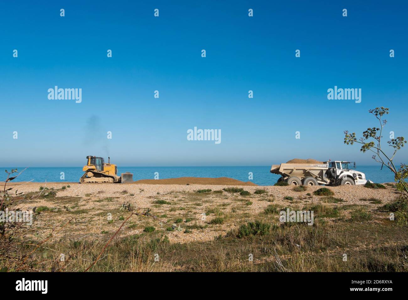 A bulldozer and dumper truck shifting the shingle up the beach to manage the effects of longshore drift at Kingsdown, Deal, Kent, UK Stock Photo