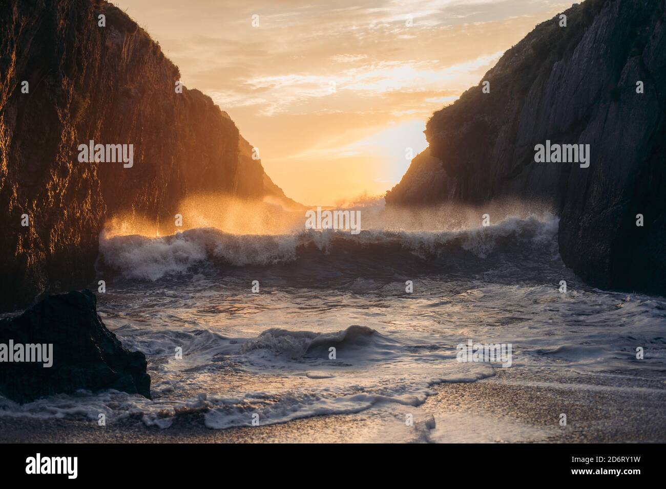 Powerful blue breaking ocean waves with white foam on sunset background Stock Photo