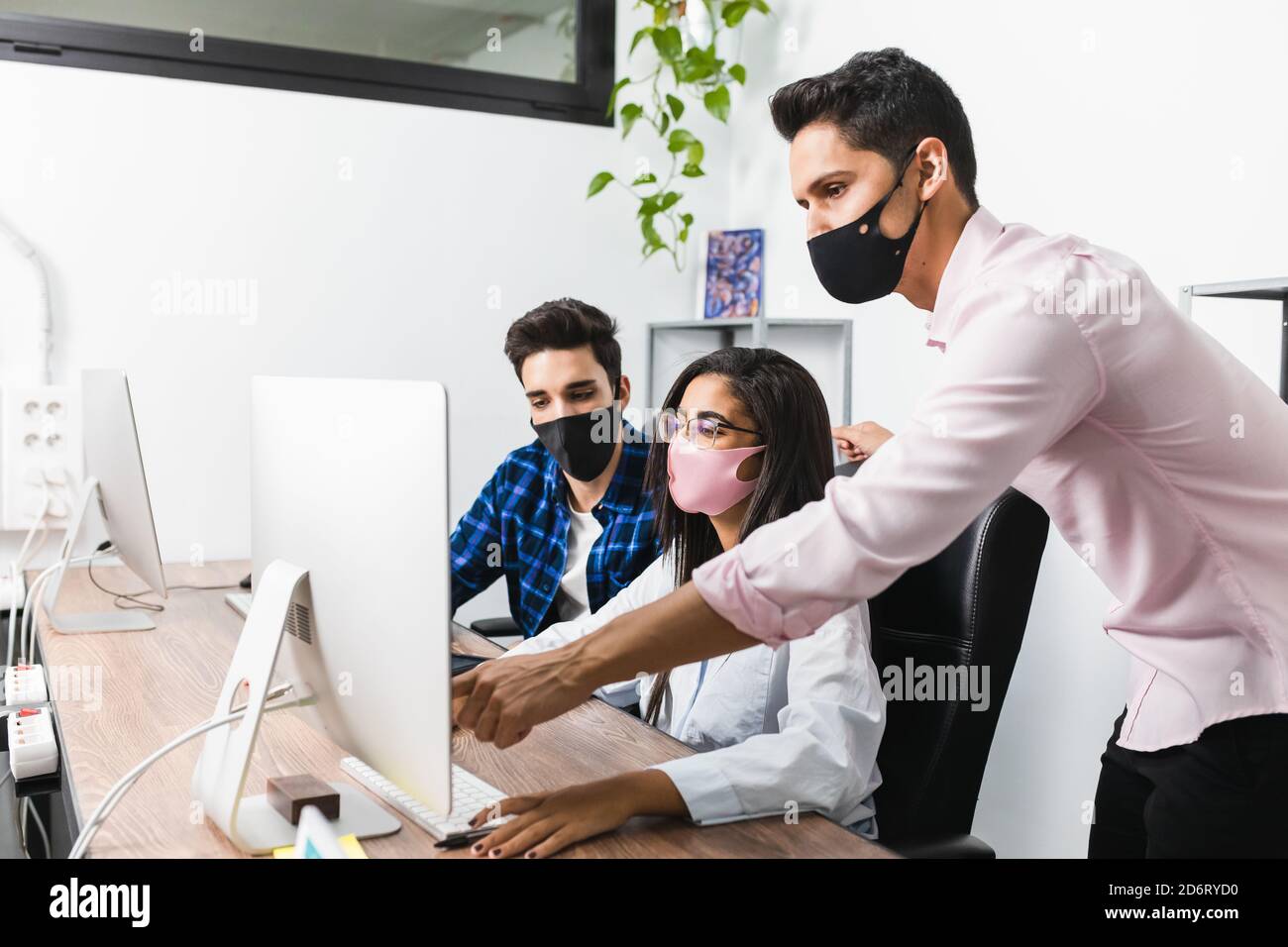 Anonymous entrepreneur in mask showing project on desktop computer ...