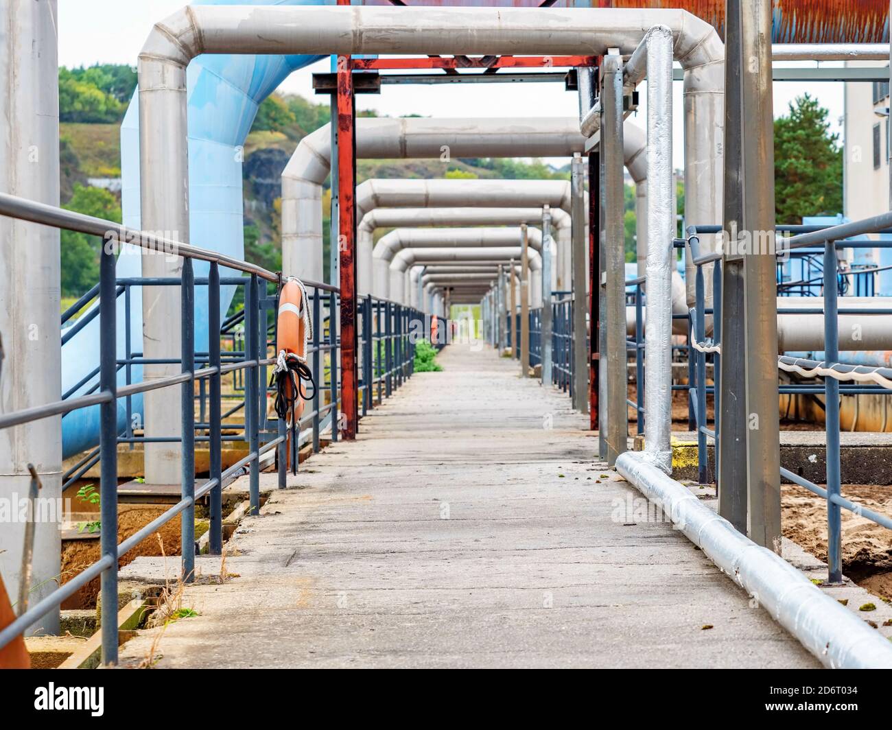 Industrial pipelines in loop on pipe bridge. Tanks field of city wastewater treatment company. Stock Photo