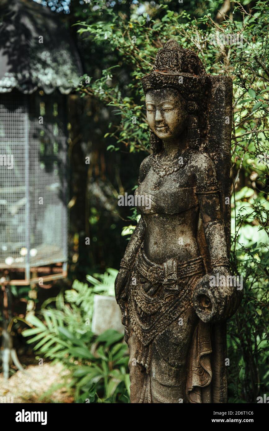Thailand - 2019. Phuket Botanic Garden. Monument of stone woman in ancient style among green leaves in botanical garden. Background blurred for artist Stock Photo