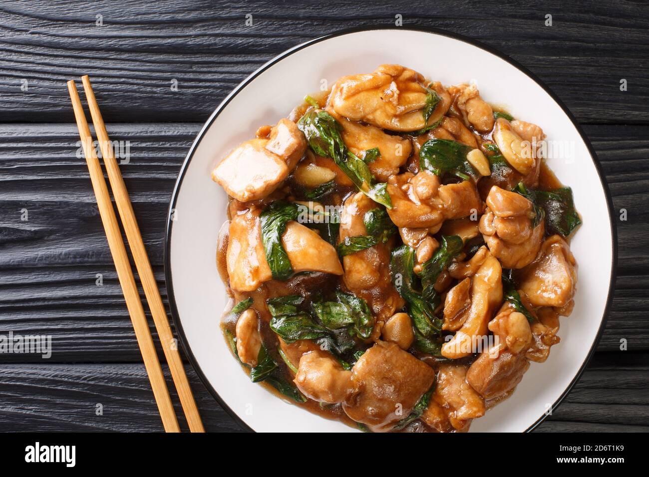 Chinese cuisine three cup chicken in a spicy sauce with basil close-up in a plate on the table. horizontal top view from above Stock Photo