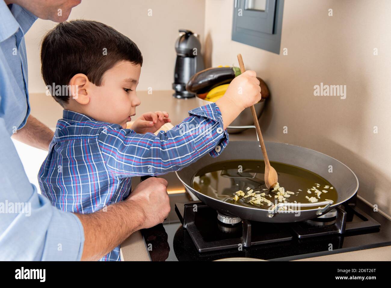 Side view cute concentrated boy stirring garlic on frying pan while