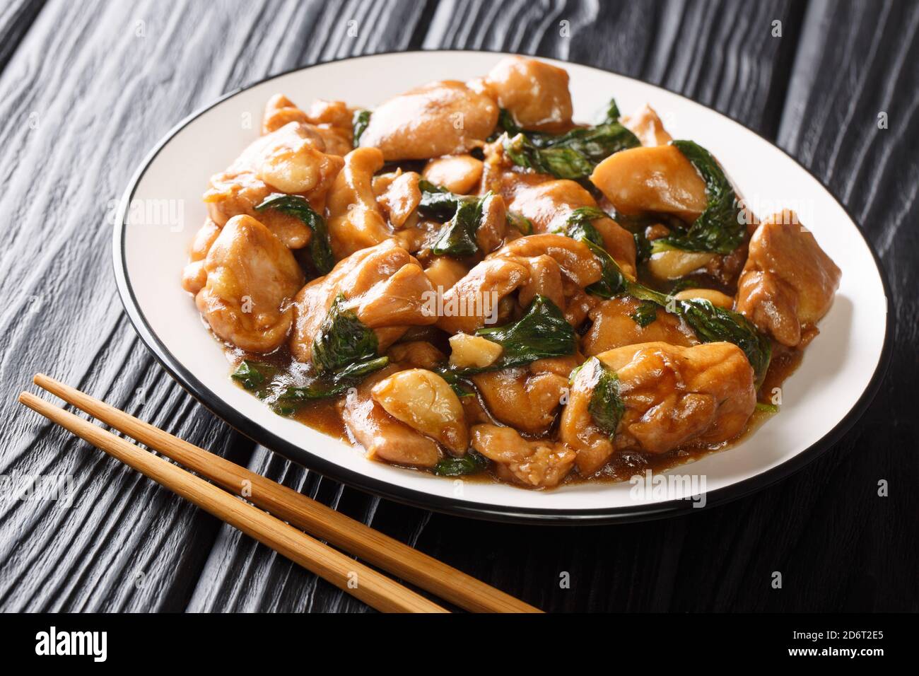 Chinese cuisine three cup chicken in a spicy sauce with basil close-up in a plate on the table. horizontal Stock Photo