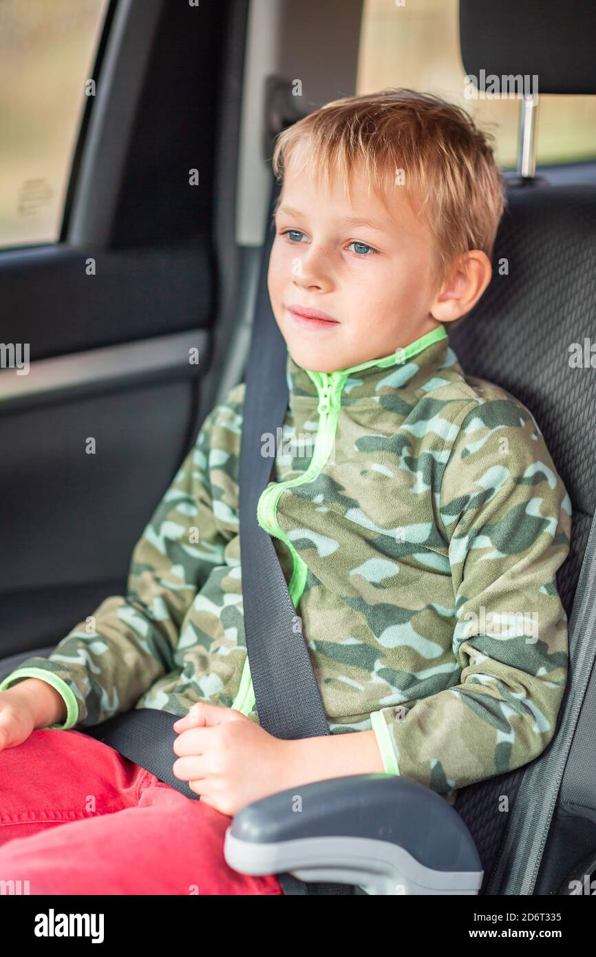 Little boy sitting on a booster seat buckled up in the car. Children's