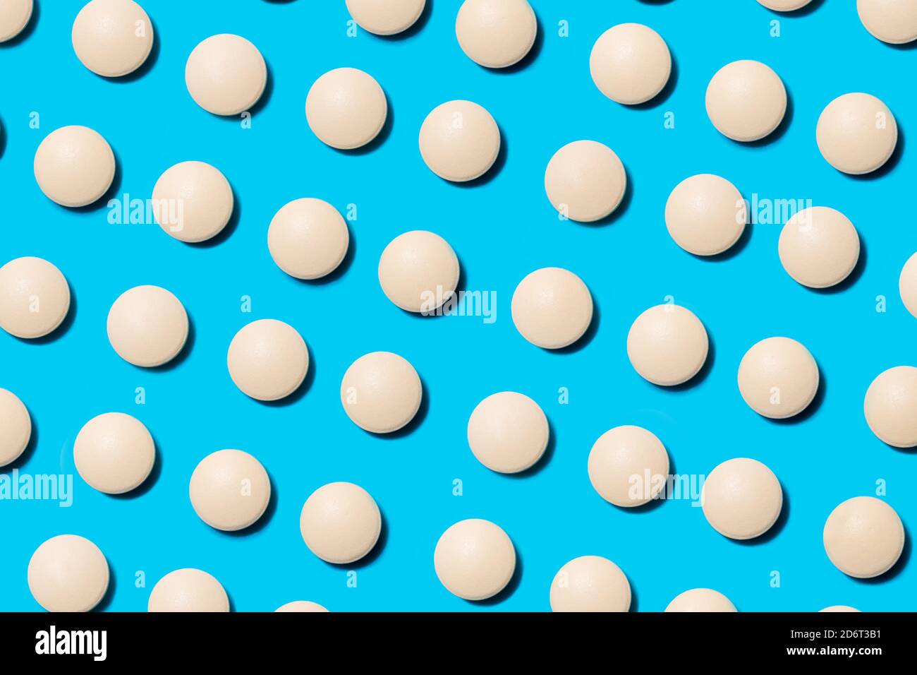 lots of white pills on a blue background. Stock Photo