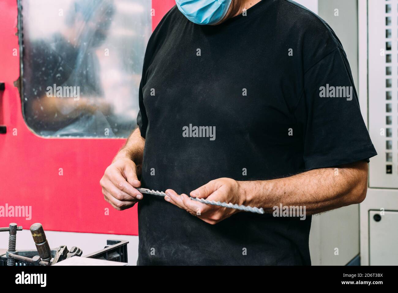 Crop unrecognizable workman with drill in hands standing in modern service center Stock Photo