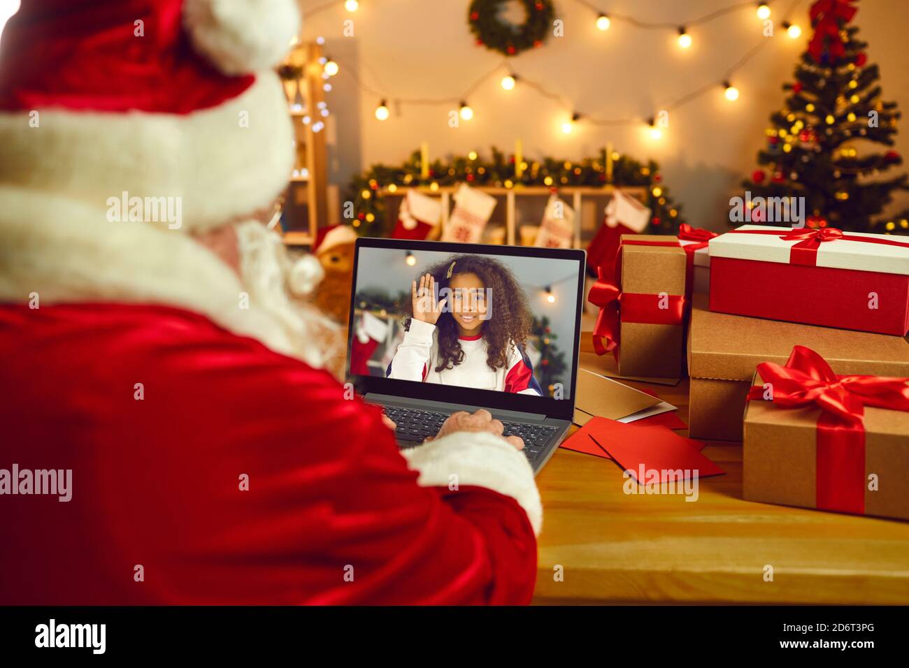 Santa Claus video calling a happy African American girl to wish her Merry Christmas Stock Photo