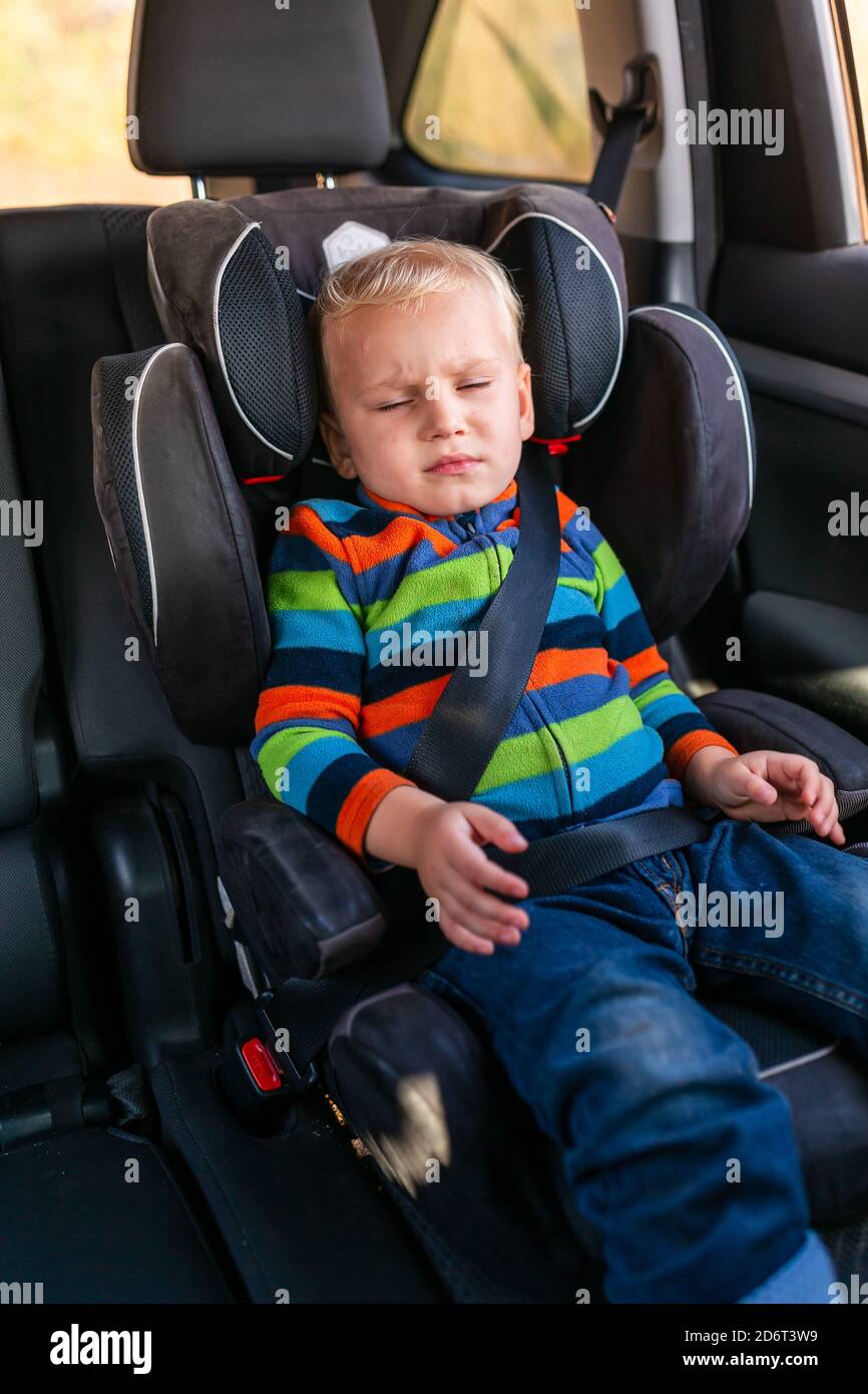 Little baby boy sleeping in his car seat buckled up in the car