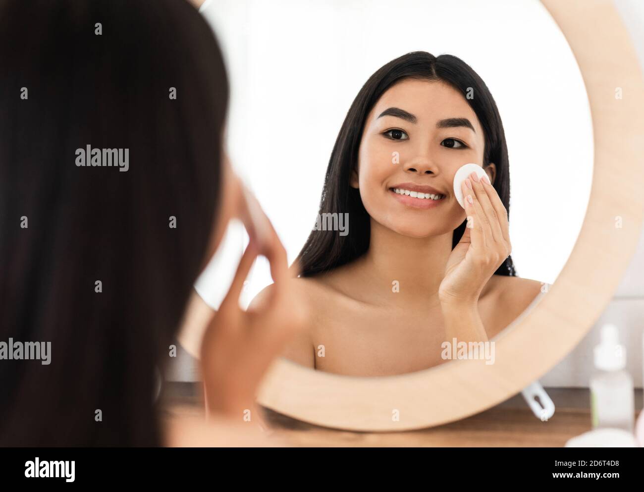 Smiling asian woman cleaning her face, using cotton pads Stock Photo