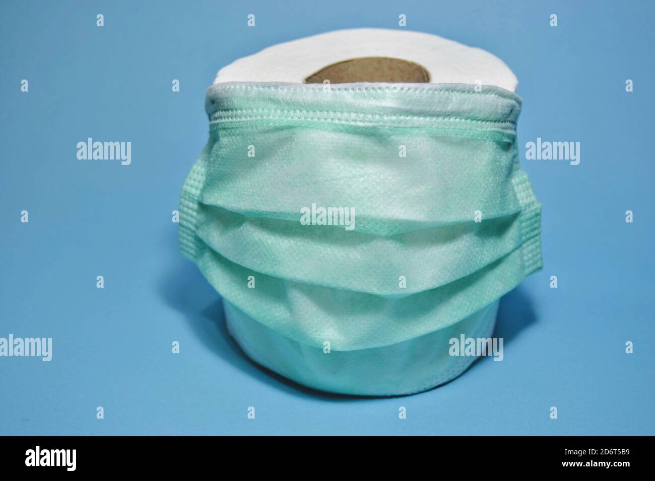 The two most discussed objects in 2020: mask and toilet paper. A photo includes green medical mask and white toilet tissue. Stock Photo
