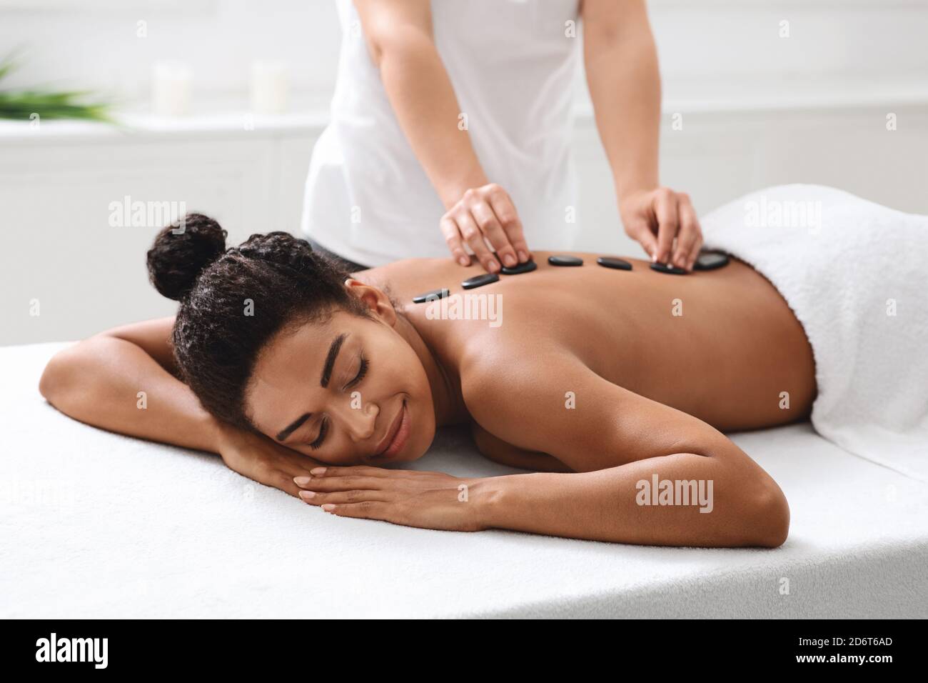 African american woman having hot stone massage at spa Stock Photo