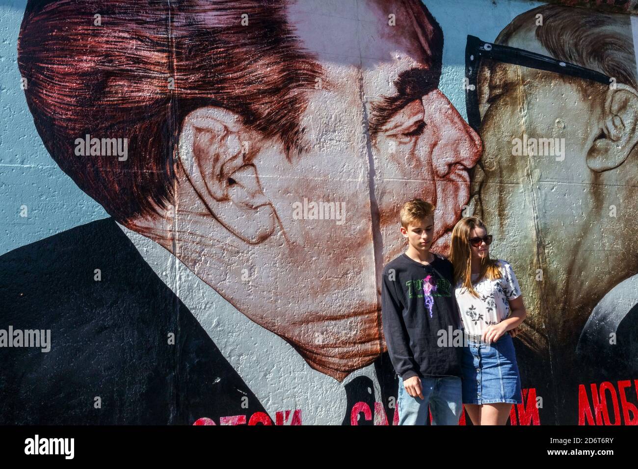 Young Couple at Graffiti on the original section of Berlin Wall at the East Side Gallery  Friedrichshain Berlin Germany graffiti wall city street art Stock Photo