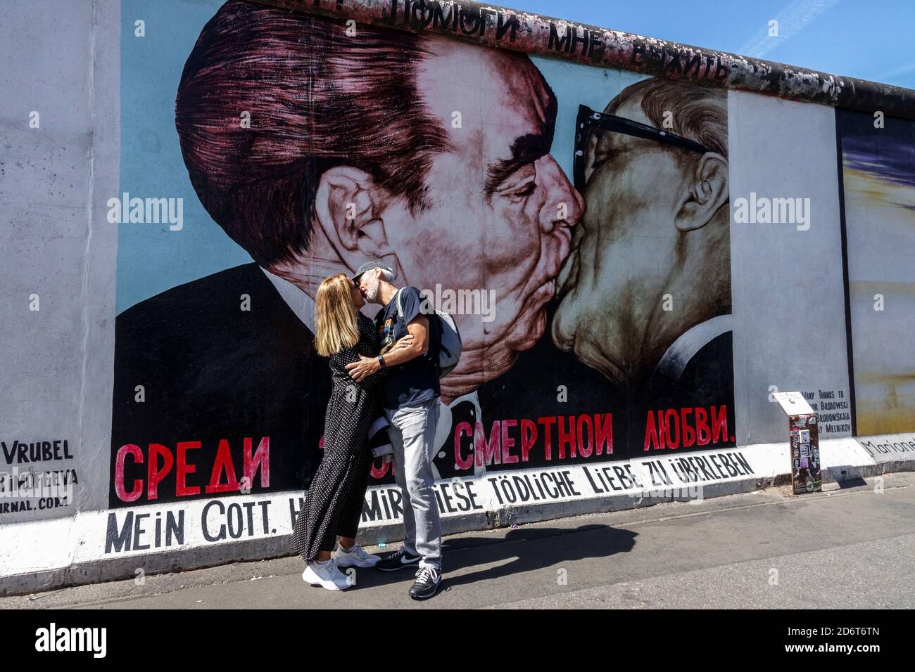 Kissing at Berlin wall graffiti on the original section of Berlin Wall at the East Side Gallery Berlin Friedrichshain Germany city street art Stock Photo