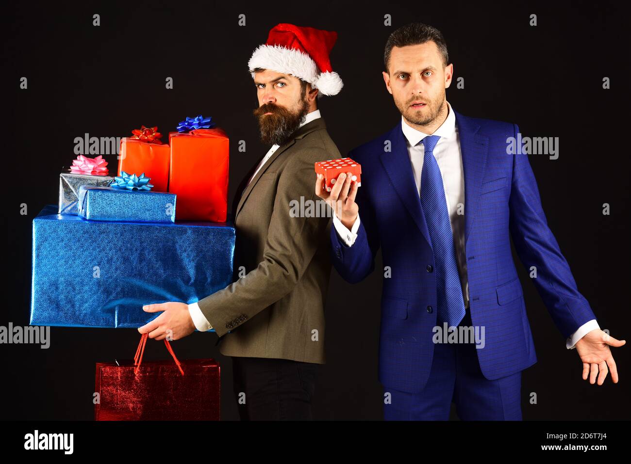 Christmas online shopping concept. Man in smart suit holding little box. Serious businessman holding big boxes and shopping bags isolated on black background Stock Photo