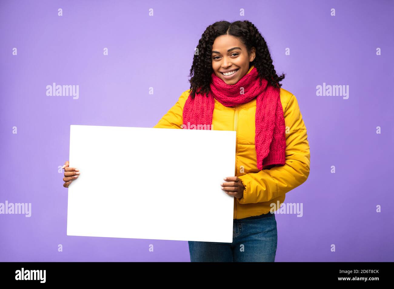 African American Woman Holding Blank Board Posing Over Purple Background Stock Photo