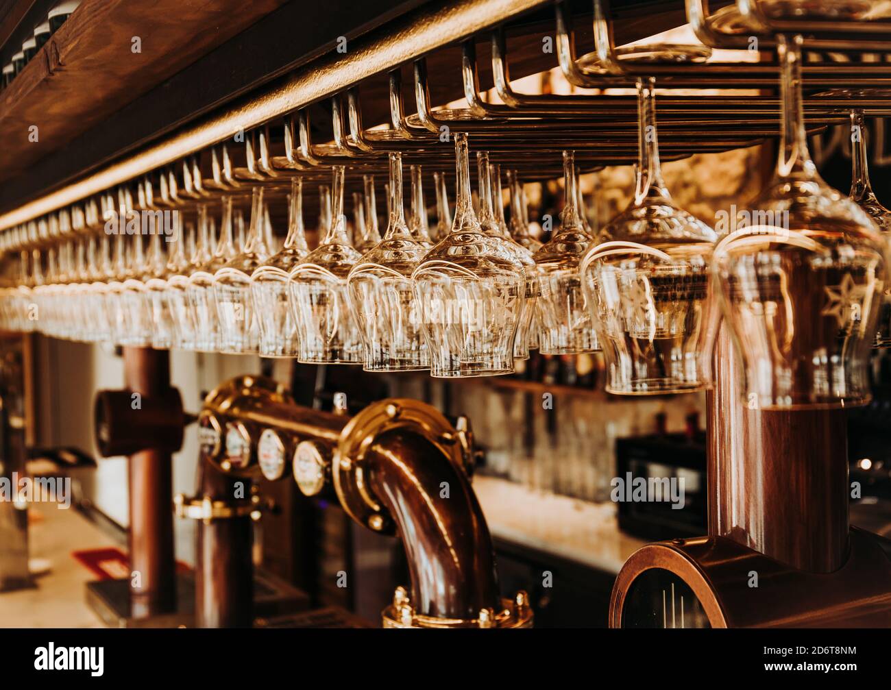 Interior of bar with shiny glasses hanging on metal rack over draught beer  taps in restaurant In Madrid Stock Photo - Alamy