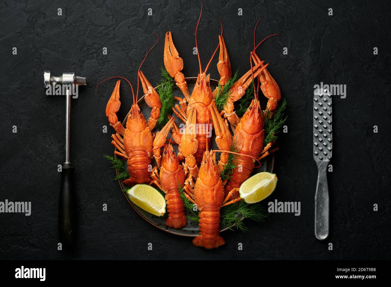 Boiled Crayfish on black plate on dark slate table top. Red crawfish with green dill and lime is popular party dish. Top view Stock Photo