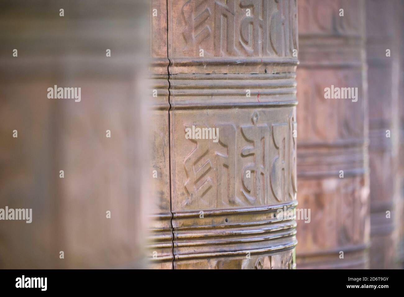 Old stone Tibetan rolls with sacred mantra consisting of sanskrit inscription near temple Stock Photo