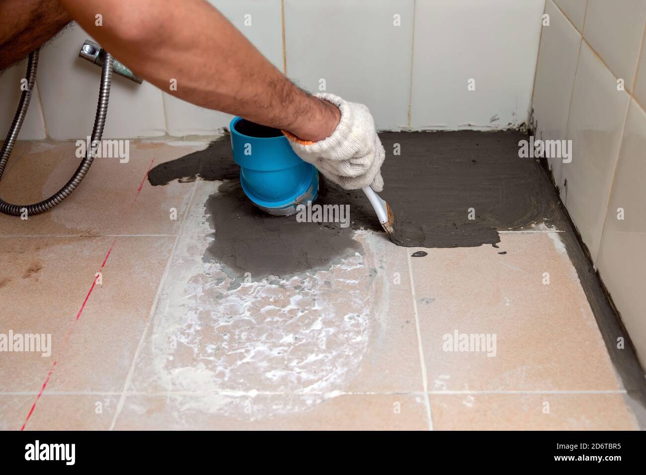 Construction workers are brushing waterproofing cement on tile floors
