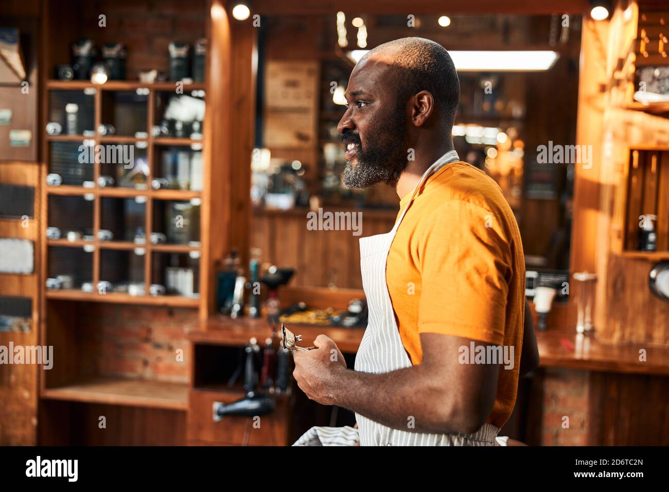 Handsome Afro American man with hair trimmer standing in barbershop Stock Photo