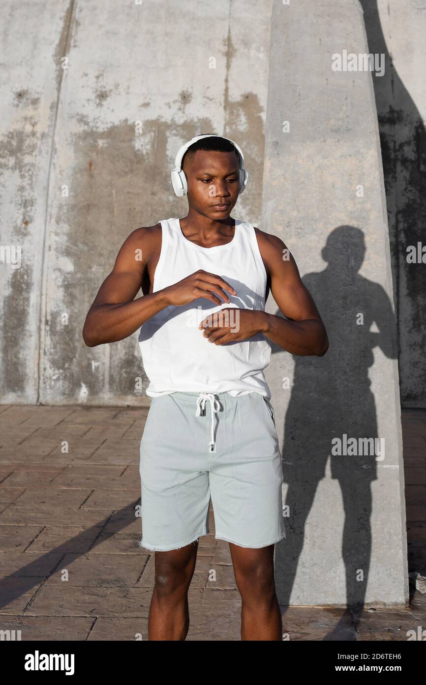 Confident African American runner warming up and doing stretching exercise while preparing for active training Stock Photo