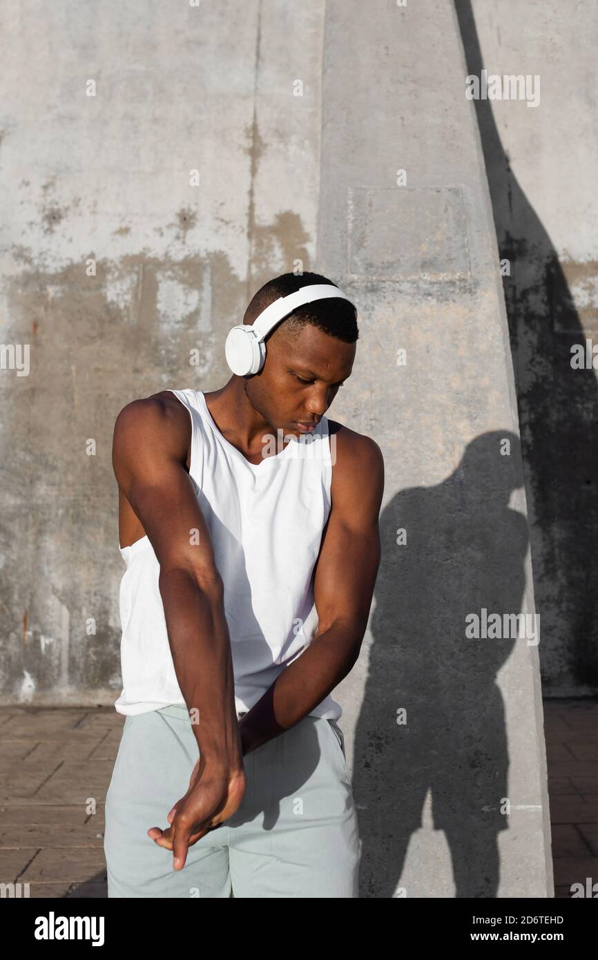 Confident African American runner warming up and doing stretching exercise while preparing for active training Stock Photo