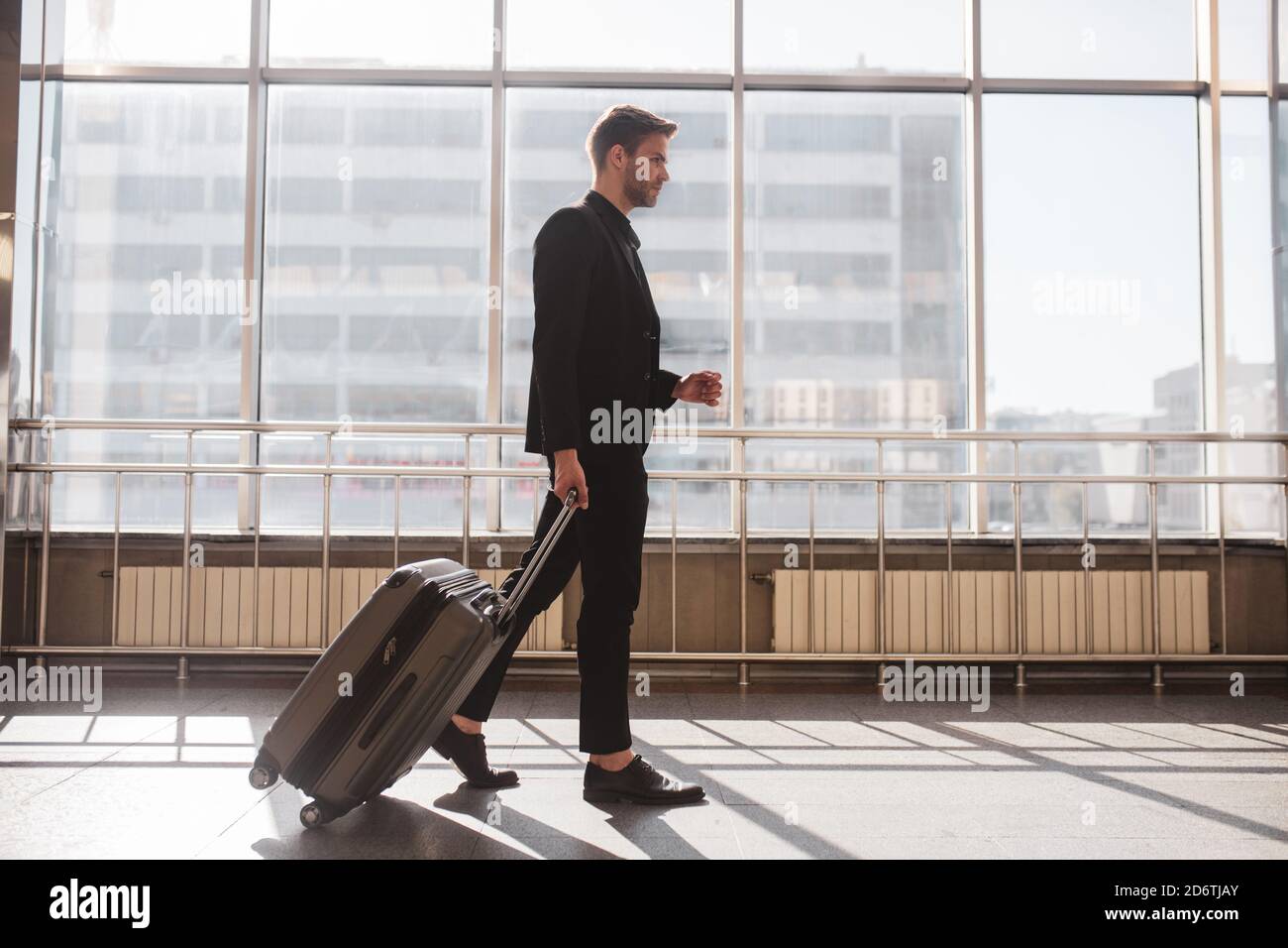 Man walking through the airport with his suitcase Stock Photo - Alamy