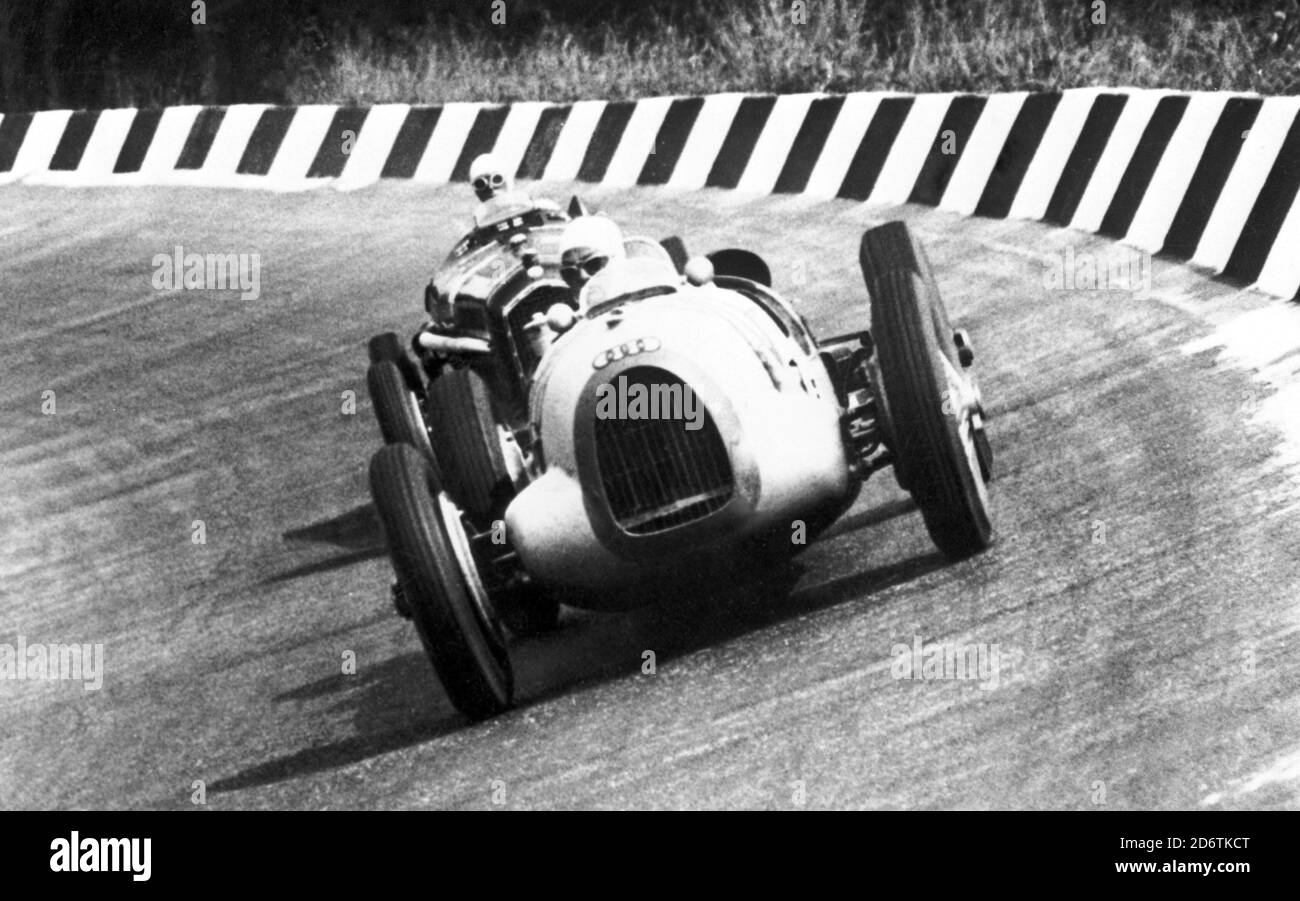 The driver Tazio Nuvolari on an Alfa Romeo is tailing a competitor on the Auto Union, Monza Grand Prix, 1930s. --- Il pilota Tazio Nuvolari su Alfa Romeo tallona un concorrente su Auto Union, Gran Premio di Monza, Anni 30. Stock Photo