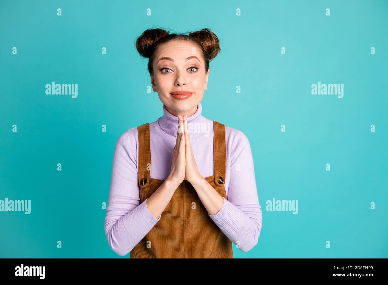 Photo of lovely shiny lipstick two buns hairstyle lady apologize begging forgiveness palms folded together wear violet pullover brown corduroy overall Stock Photo