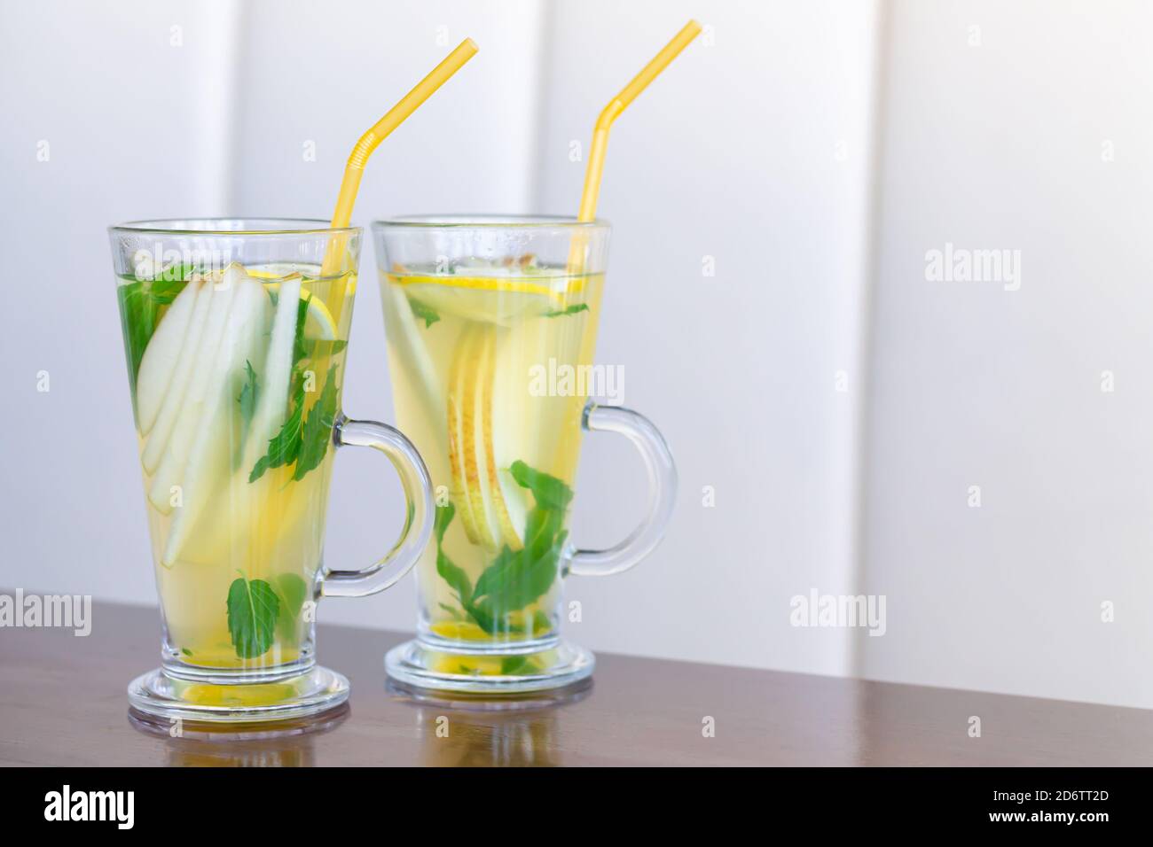 https://c8.alamy.com/comp/2D6TT2D/two-glass-cups-of-fruit-tea-with-mint-lemon-pear-honey-and-ginger-on-wooden-table-2D6TT2D.jpg