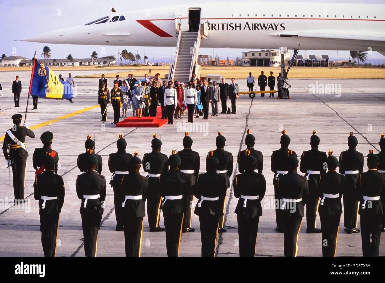 Britain's Queen Elizabeth II standing on the red carpet during a welcome ceremony after landing at Grantley Adams International Airport on a B.A. Concorde flight at the start of her four-day visit to the Caribbean Island of Barbados. March 8, 1989. Stock Photo